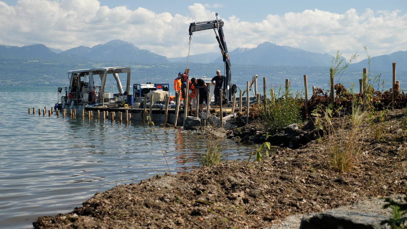 Battage de pieux depuis une barge, devant les Alpes